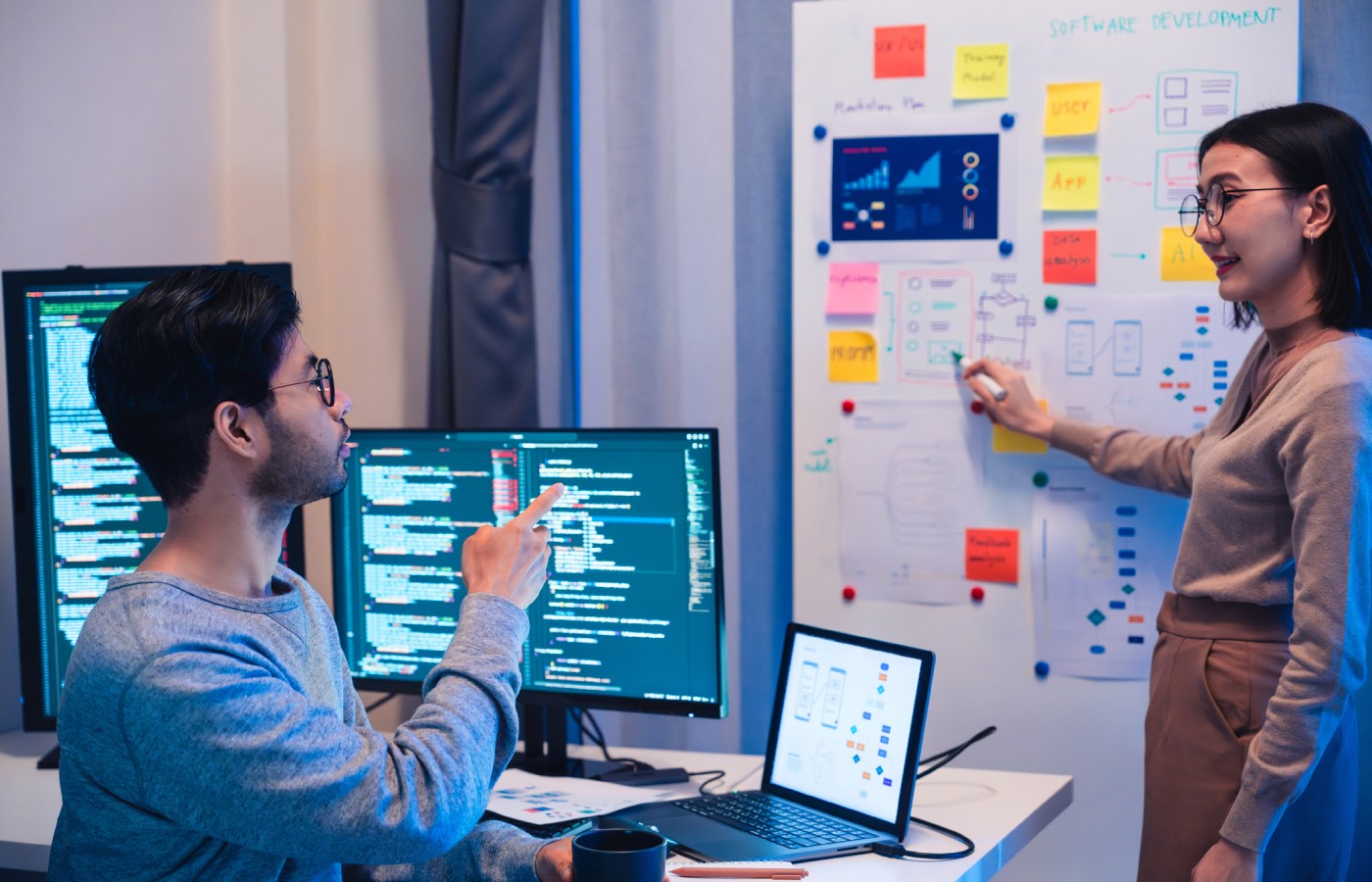Agile software team collaborating on code and visual planning board, showing sprint tasks and user flows.