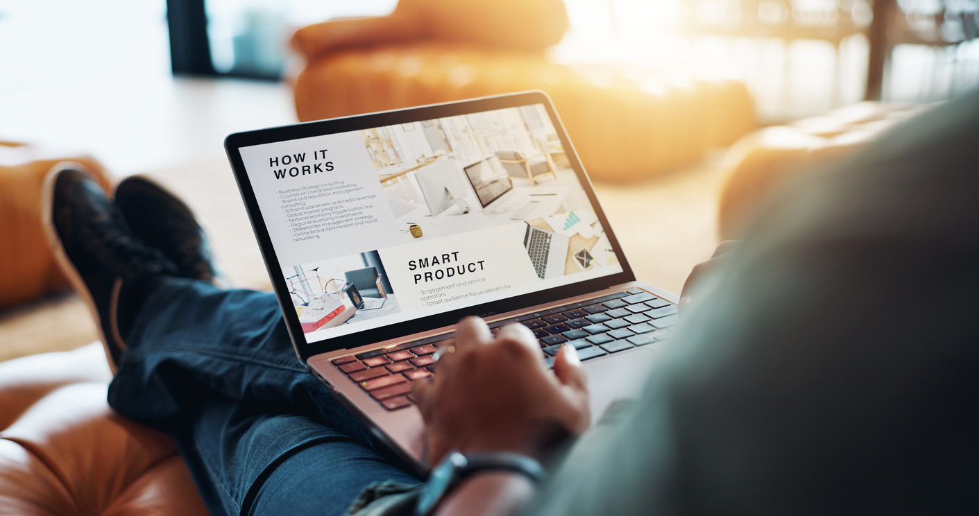 A laptop with a website on the screen sits on a mans legs.
