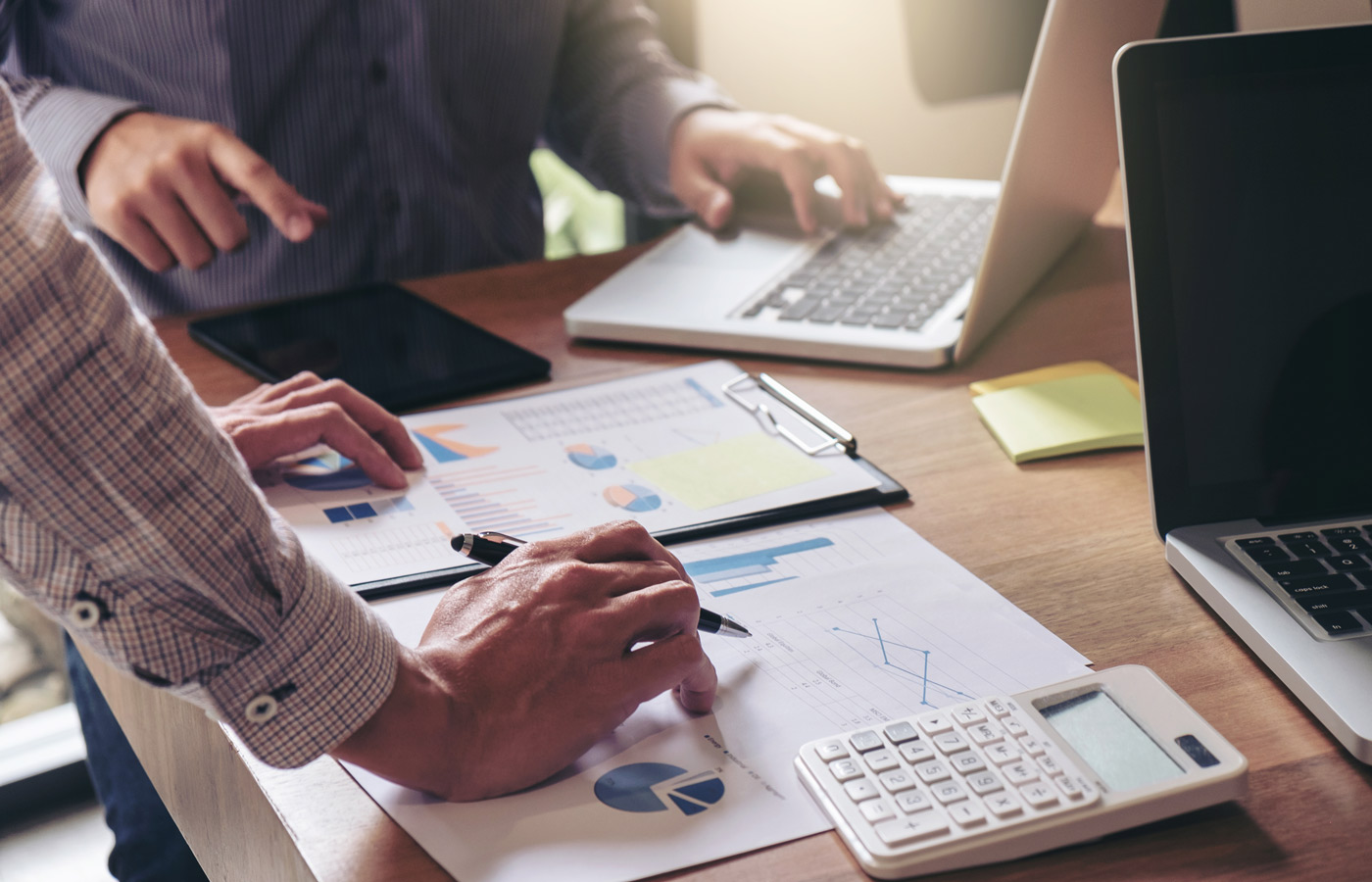 Arms stretch over a table as a team works on their strategy and business process.