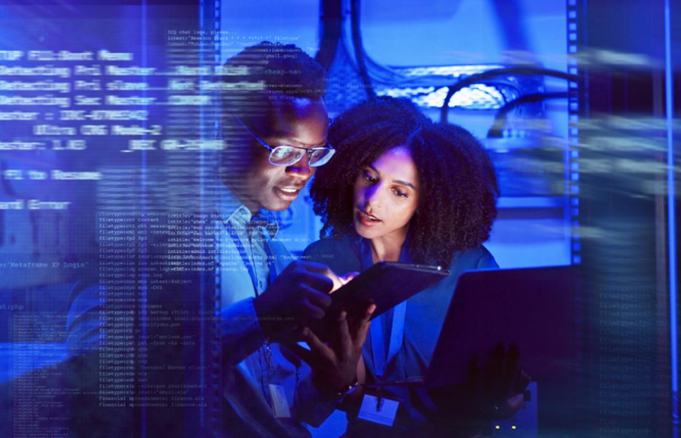 Two professionals look at a tablet together with code overlaying the image.